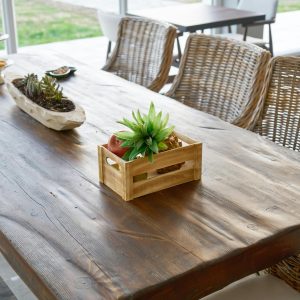 Cozy indoor dining setup with a rustic wooden table adorned with plants and wicker chairs.