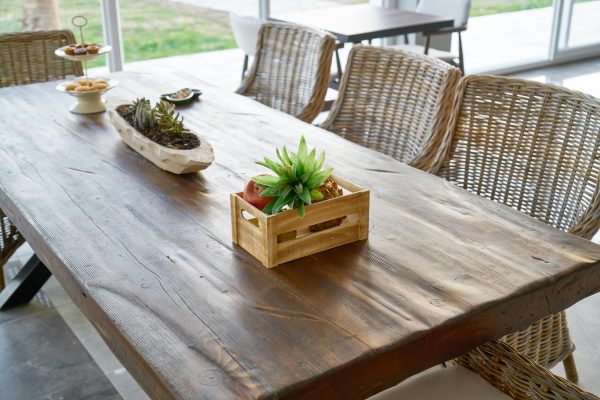 Cozy indoor dining setup with a rustic wooden table adorned with plants and wicker chairs.